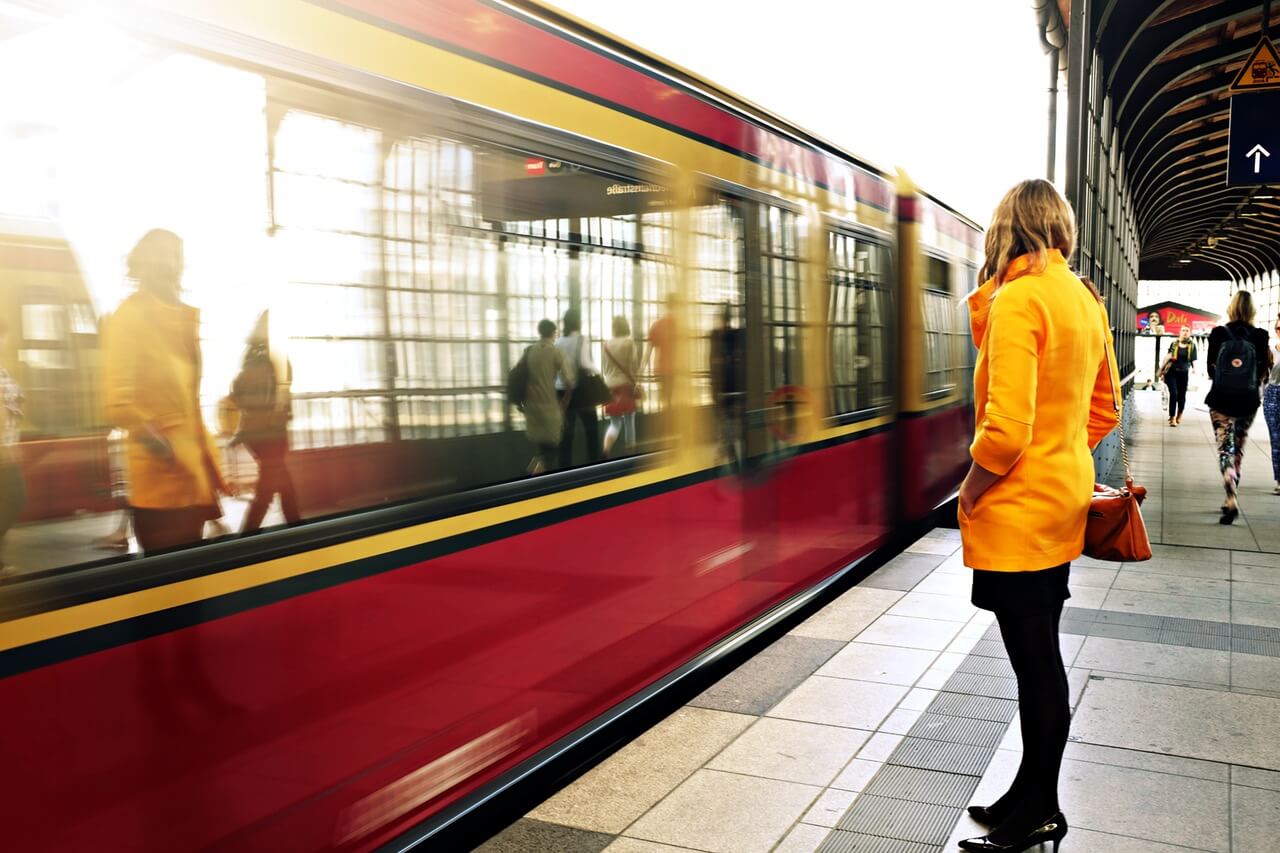 A woman in a yellow jacket standing on a train platform.